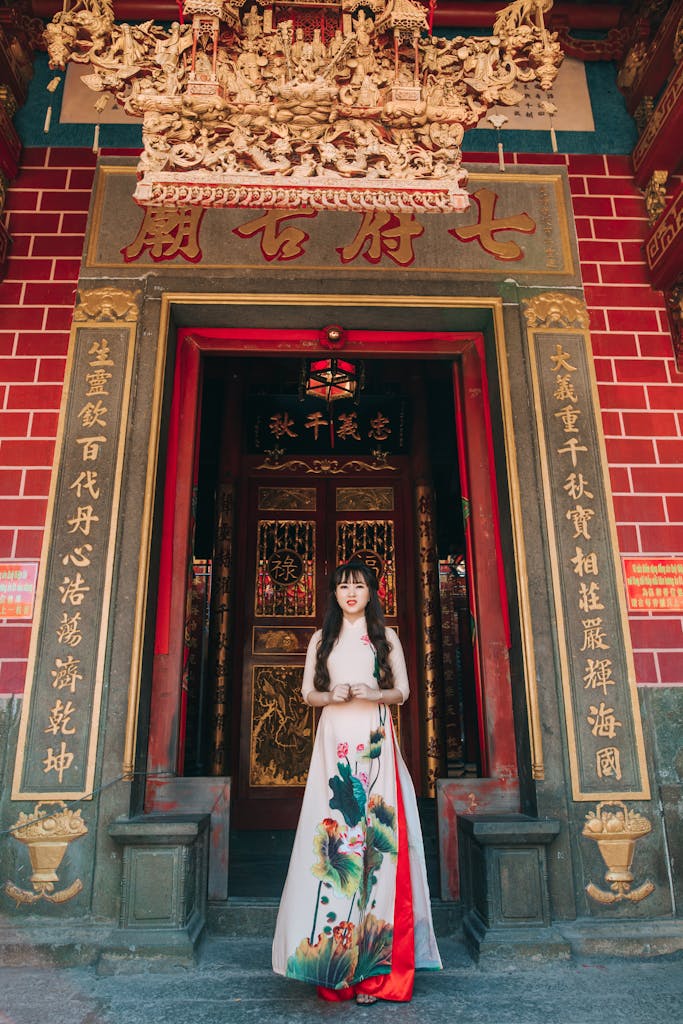 Adult woman in traditional dress stands at a temple entrance, showcasing intricate architecture.